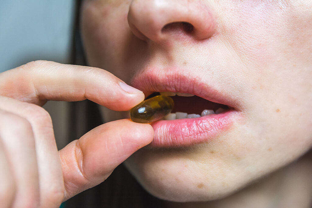 closeup-shot-of-a-pill-between-a-womans-teeth