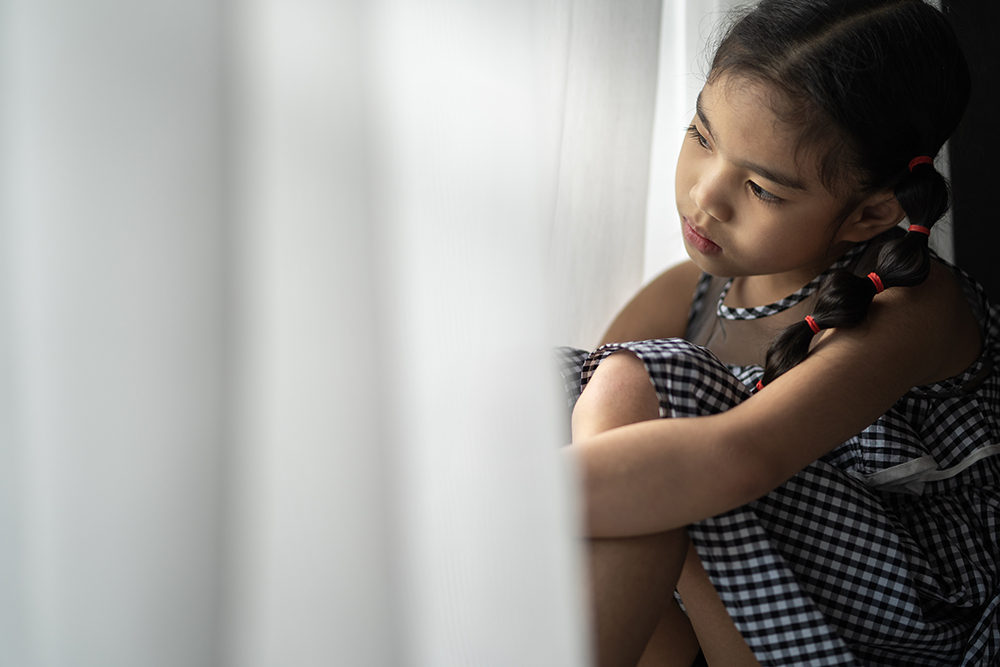 depressed-little-girl-near-window-at-home-closeup